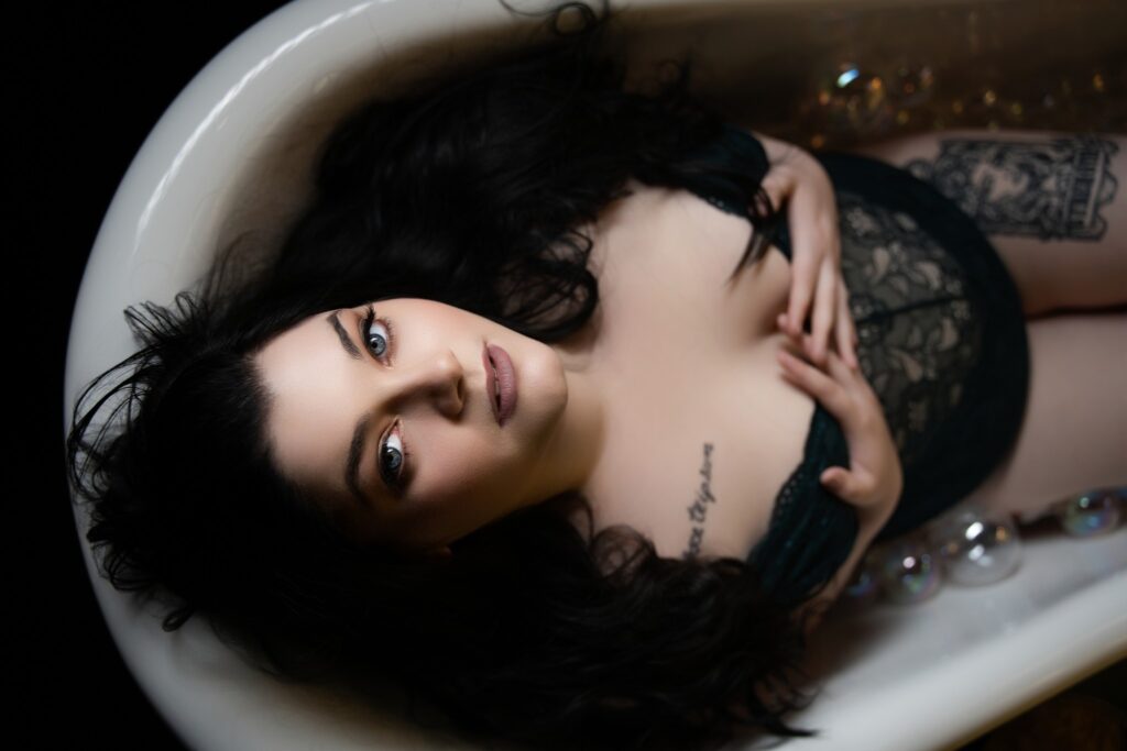Closeup of a woman’s face during boudoir shoot, sparkling eyes and soft self-embrace
